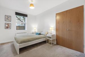 ロンドンにあるSpacious Clapham Apartmentsのベッドルーム1室(ベッド1台付)、木製キャビネットが備わります。