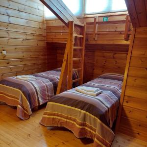 two beds in a room with wooden walls at Koli Country Club in Hattusaari