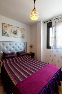 a bedroom with a large bed with a purple blanket at Kings House in Almería