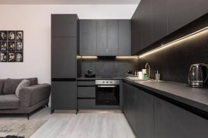 a kitchen with black cabinets and a couch in it at Kapana Beat 2-bedroom apt. Top Center in Plovdiv