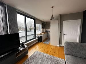 a living room with a flat screen tv and a kitchen at Luxury Penthouse Apartment in Uxbridge