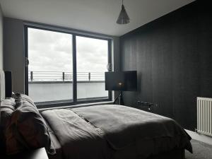 a bedroom with a bed and a large window at Luxury Penthouse Apartment in Uxbridge