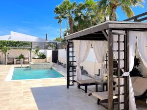 een huis met een zwembad en een pergola bij Aruba Lagunita in Palm-Eagle Beach
