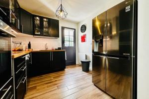 een keuken met zwarte kasten en een roestvrijstalen koelkast bij The House of Heathers in Athée-sur-Cher