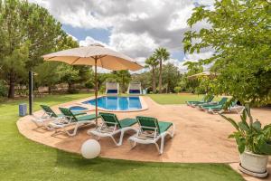 uma piscina com cadeiras e um guarda-sol e uma piscina em La Forca - Lujosa villa con mucha privacidad em Santa Margalida