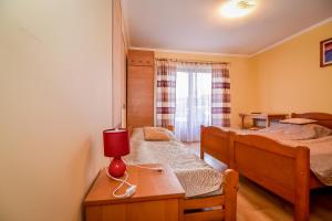 ビャウィ・ドゥナイェツにあるCudzichówkaのベッドルーム1室(ベッド2台、テーブル上の赤いランプ付)