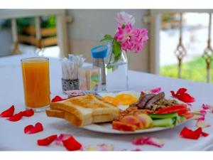 a plate of food with bread and fruit and a glass of orange juice at Gorilla African Guest House in Entebbe