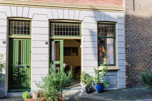 biały budynek z zielonymi drzwiami i roślinami z przodu w obiekcie B&B À la Lon w mieście Dordrecht