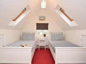 two beds in a room with a red carpet at 4 Bed in Corfe Castle 62985 in Worth Matravers