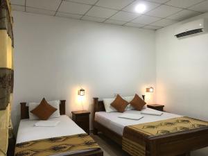 Habitación con 2 camas y 2 lámparas en la pared. en Sigiri Cardamon Villa en Sigiriya