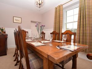 a dining room with a wooden table with wine glasses at 5 bed in Chirnside 77337 in Duns