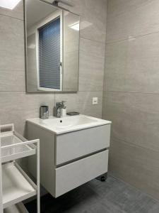 Baño blanco con lavabo y espejo en LabPark Relax Apartment, en Melano