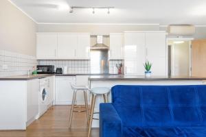 a kitchen with white cabinets and blue chairs at 221 Clapham Road Apartments in London