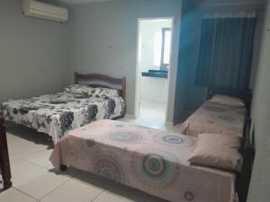 a room with three beds in a room with a hallway at Casalagoana in Marechal Deodoro