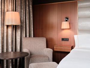 een slaapkamer met een bed, een stoel en een tafel bij The Westin Warsaw in Warschau