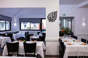 uma sala de jantar com mesas brancas e cadeiras pretas em Hôtel Hélianthe em Lourdes