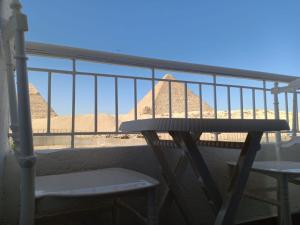 uma varanda com uma mesa e duas cadeiras e as pirâmides em Yamour Pyramids View no Cairo