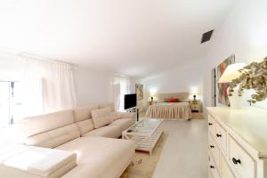 a white living room with a couch and a bed at Alojamiento Rural Finca Barral in Seville