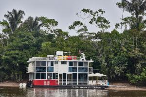 un barco en un río con árboles en el fondo en El Manatí - River Experience, en Iquitos