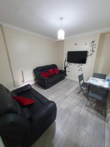 ein Wohnzimmer mit einem schwarzen Sofa und einem TV in der Unterkunft House In the heart of valleys in Ebbw Vale