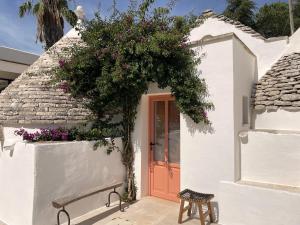 Biały dom z czerwonymi drzwiami i kwiatami w obiekcie Trullo Panna Fragola - Exclusive four bedroom Villa & Private pool w mieście Martina Franca