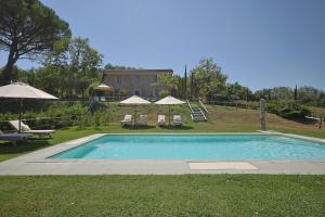 una piscina con due sedie e ombrelloni di Gio Toscana a Castiglione della Pescaia