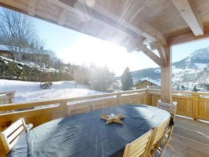 a table and chairs on a deck with snow on the ground at Chalet Le Grand-Bornand, 7 pièces, 11 personnes - FR-1-391-91 in Le Grand-Bornand