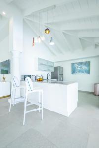 biała kuchnia z 2 krzesłami i blatem w obiekcie La Perla Estate - 7 BR Luxury Beachfront Villa with utmost privacy w mieście Les Terres Basses