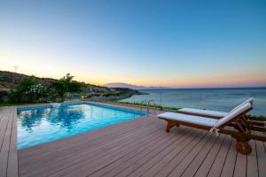 una piscina con un banco en una terraza con el océano en Villa Vrahos - Deja Vu Villas, en Agios Nikolaos
