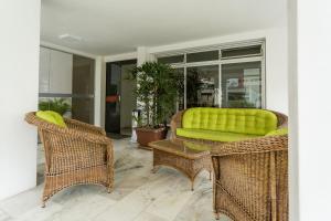 a patio with wicker chairs and a green couch at Ao lado do Shopping e da Beiramar Norte GB1800 in Florianópolis