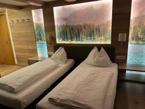 two beds in a room with paintings on the wall at Gasthof Zur Sonne in Cardano +63 photos