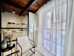 a white kitchen with a chair and a window at I Granai - Marea Collection in Nardò