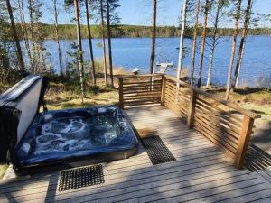 a hot tub on a wooden deck next to the water at Villa Vaskela in Virrat