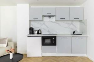 a kitchen with white cabinets and a black microwave at Chapelle/Ordener : Magnifique appartement 1BR/4P in Paris