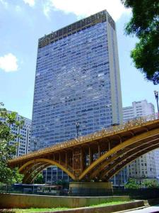 a tall building with a bridge in front of it at Loft 37 Centro histórico in Sao Paulo