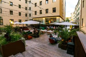 un patio con tavoli, sedie e ombrelloni in un edificio di The Social Hub Florence Lavagnini a Firenze