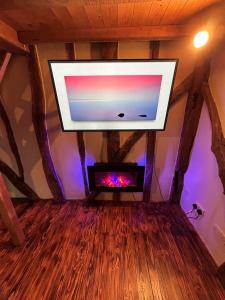 a flat screen tv in a room with a wooden floor at Cozy Cottage with hot tub! in Cadnam