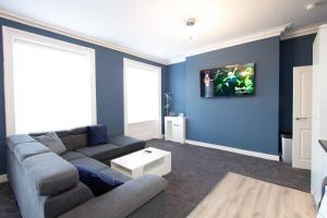 a living room with a couch and a tv on the wall at Lavish 2Bed Apartment in the Heart of Birkenhead in Birkenhead
