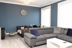 sala de estar con sofá gris y pared azul en Lavish 2Bed Apartment in the Heart of Birkenhead, en Birkenhead