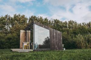 a glass house with a table in a field at Slapen aan het Wad in Rasquert