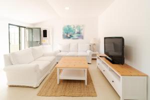 a living room with white furniture and a flat screen tv at Alojamiento Rural Finca Barral in Seville