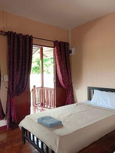 een slaapkamer met een bed en een groot raam bij คีรินรีสอร์ท in Ban Pak Chong
