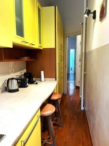 a kitchen with yellow cabinets and stools in it at Elegante appartamento in centro in Milan