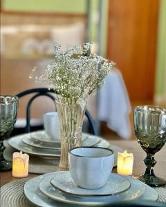 uma mesa com pratos e um vaso de flores em Apartamentos - Estúdios em São José