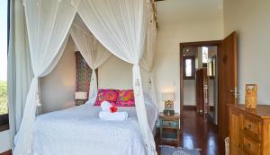 Casa Bali Ibira في إيمبيتوبا: غرفة نوم بسرير أبيض مع مظلة