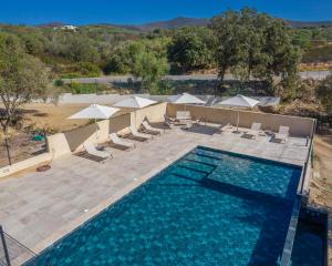 an overhead view of a swimming pool with chairs and umbrellas at Les Bergeries du Domaine de Pinelli in Belgodère