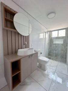 a bathroom with a sink and a toilet and a mirror at Apartamento na região céntrica in Foz do Iguaçu