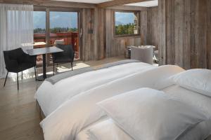Un dormitorio con una gran cama blanca y una mesa en Aïda Hôtel & Spa - "Adults Only" Relais & Châteaux en Crans-Montana