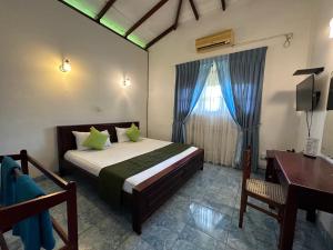 a bedroom with a bed with a desk and a window at Natures Bliss Holidays in Ja-Ela +280 photos