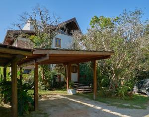 a house with a wooden pergola in front of it at Casa Bali Ibira in Imbituba